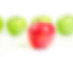 roter Apfel vor einer Reihe grüner Äpfel