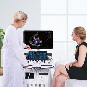 Untersuchung mit Ultraschallgerät VINNO G60 Ärztin erklärt Bild, Patientin sitzt auf der Therapieliege, beide blicken zum Gerät